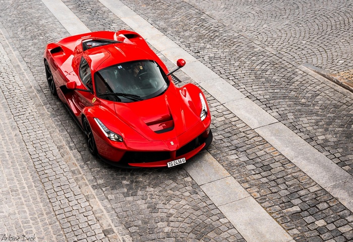 Red Ferrari LaFerrari driving on cobblestone street
