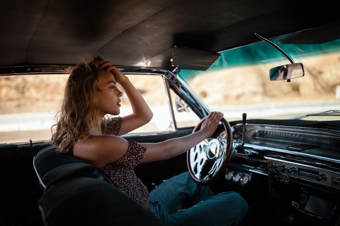 Woman with blonde hair driving a vintage car