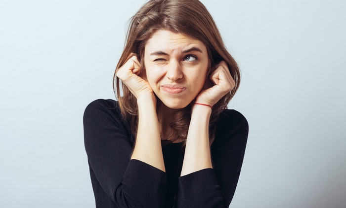 Woman covering her ears with a disgusted expression