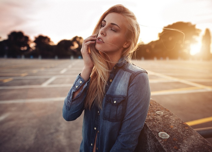 Portrait of a blonde woman in a denim shirt at sunset