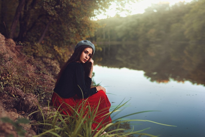 Woman in red dress and hat by the river