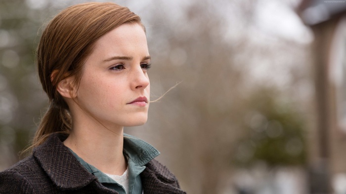 Emma Watson in a brown coat looking into the distance