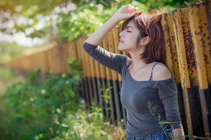 Asian woman leaning against a fence outdoors
