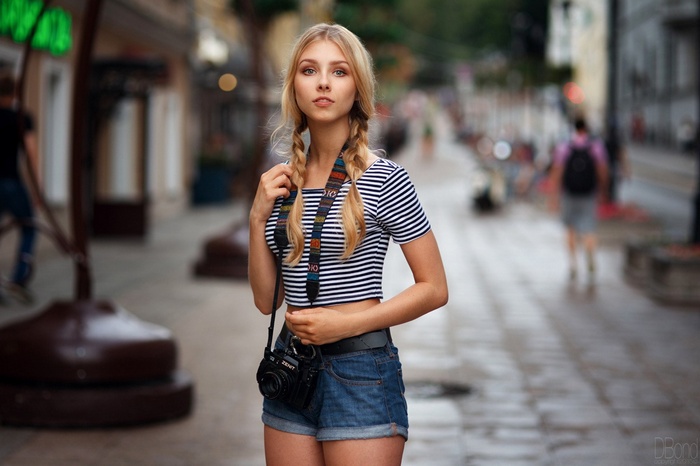 Woman with camera wearing striped crop top and jean shorts