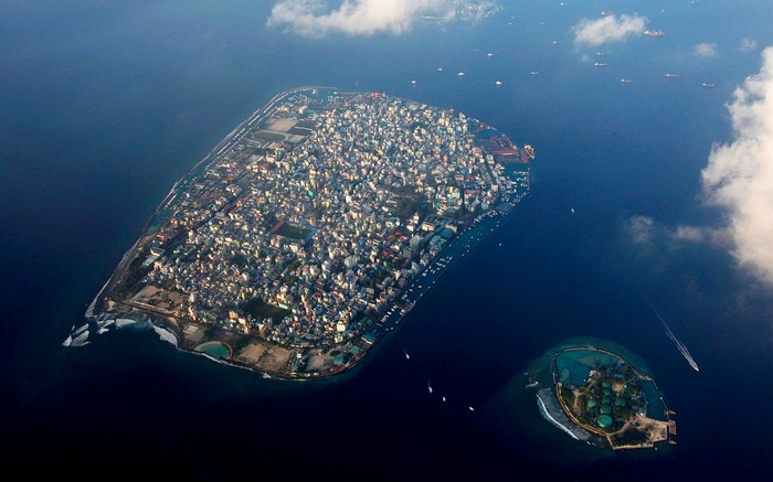 Aerial view of Malé, Maldives, with surrounding ocean and clouds