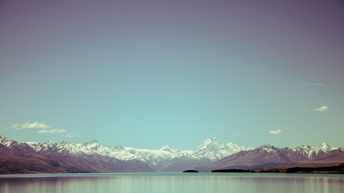 Snow-capped Alps reflected in a calm lake under a clear sky