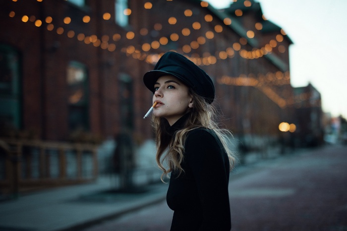 Woman in black hat smoking outdoors