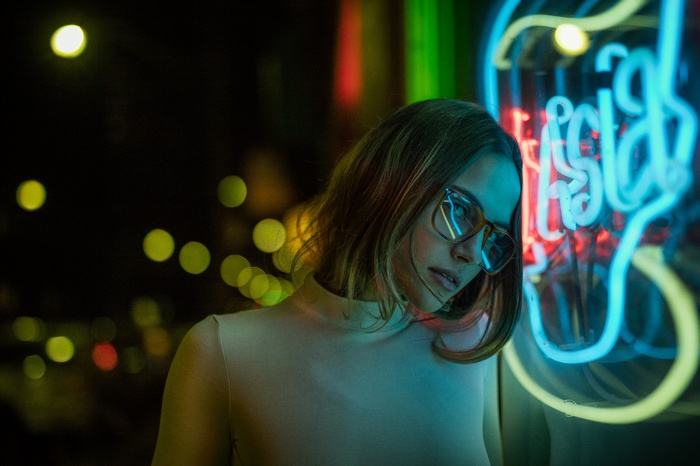 Woman with glasses in front of neon lights at night