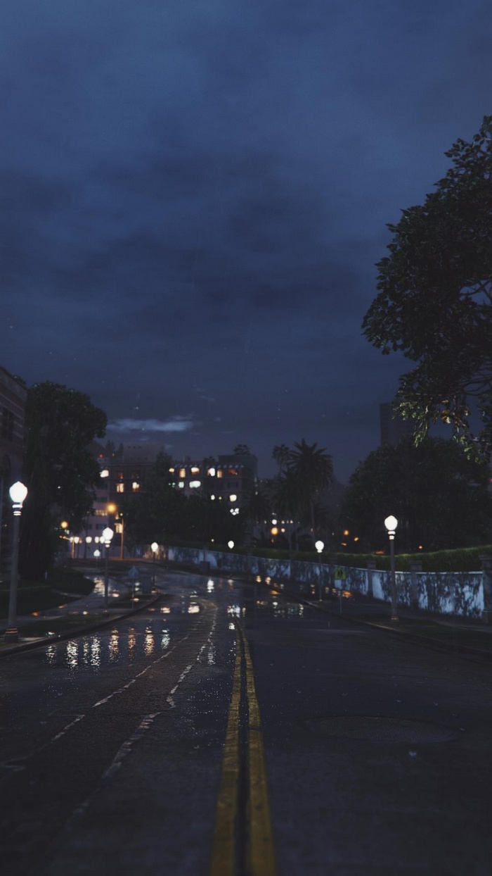 Rainy night road with city lights and dark sky