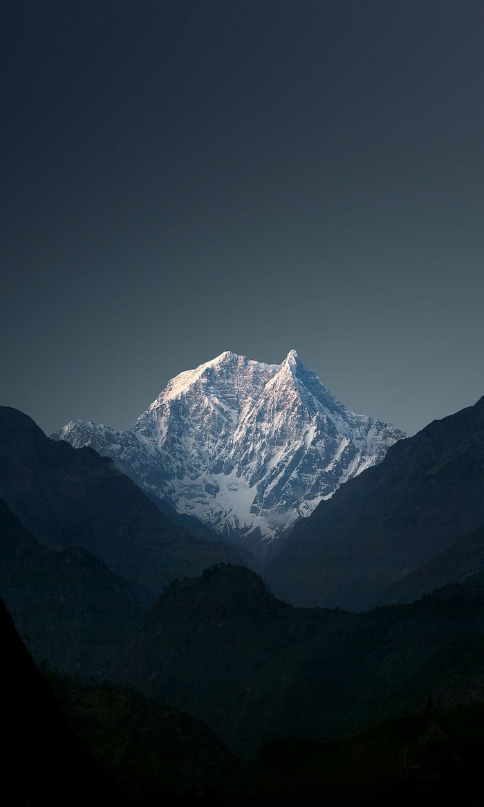 Snow-capped mountain peak under a dark sky