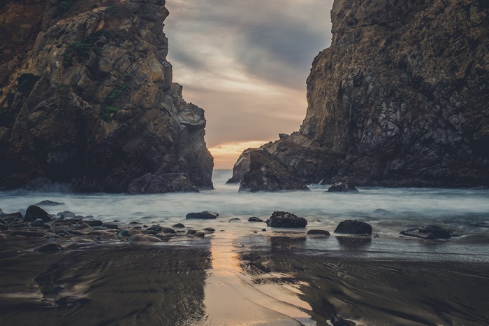 Rocky coastline with ocean waves at sunset