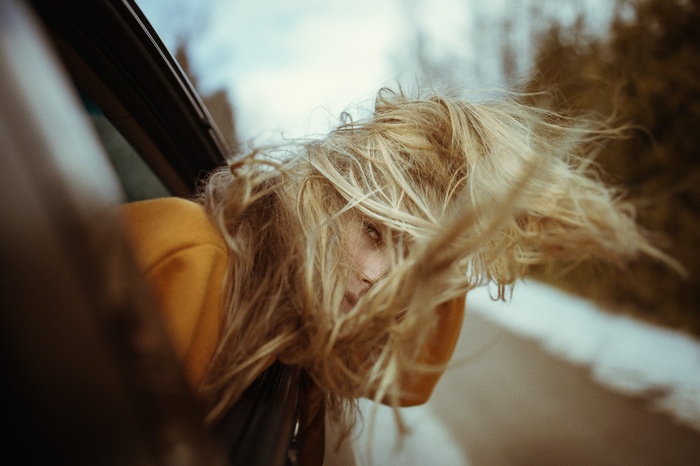 Woman with blonde hair looking out of a car window