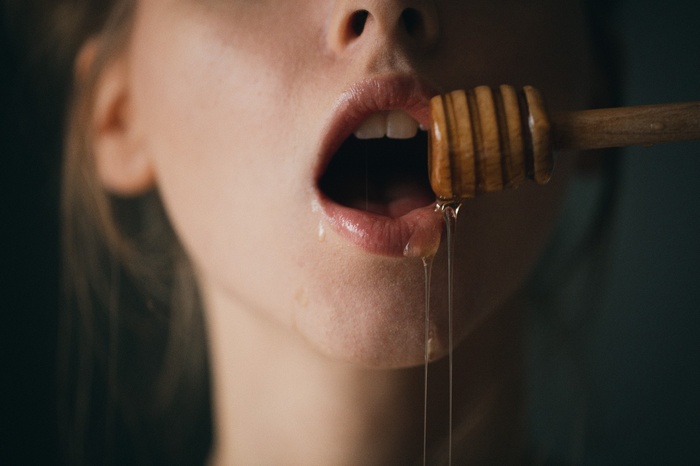 Woman with honey dipper and open mouth