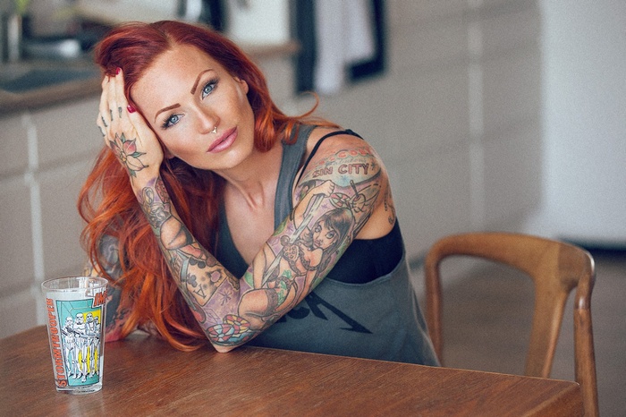 Anne Lindfjeld with tattoos and a glass