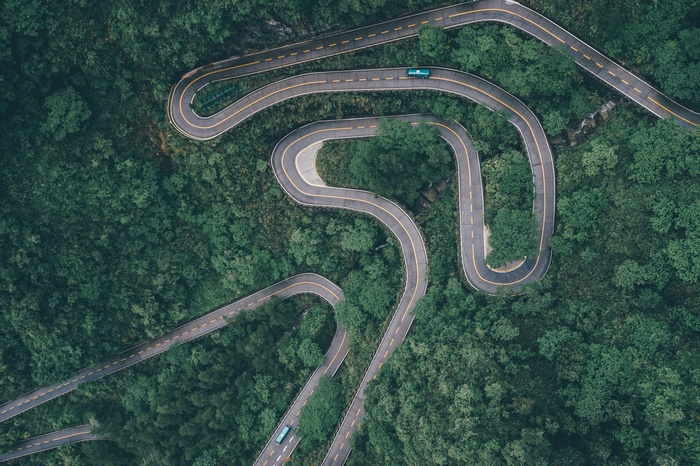 Aerial view of a winding road through a green forest in China