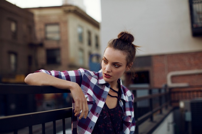 Woman in Plaid Shirt Leaning on Railing Outdoors