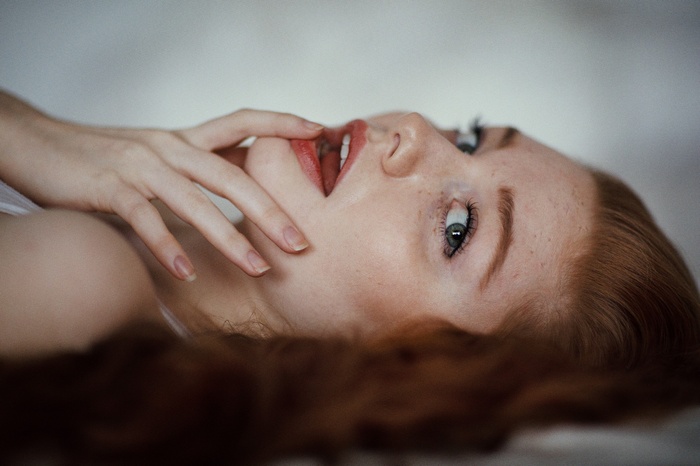 Redhead woman with freckles and blue eyes lying down