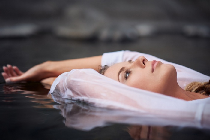 Woman floating in water wearing a white shirt