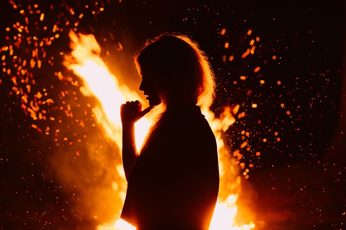 Silhouette of a woman in front of a fire