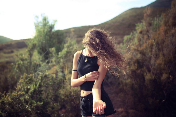 Woman with wavy hair in black top and shorts outdoors