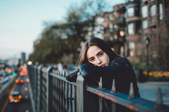 Woman leaning on a fence overlooking a street