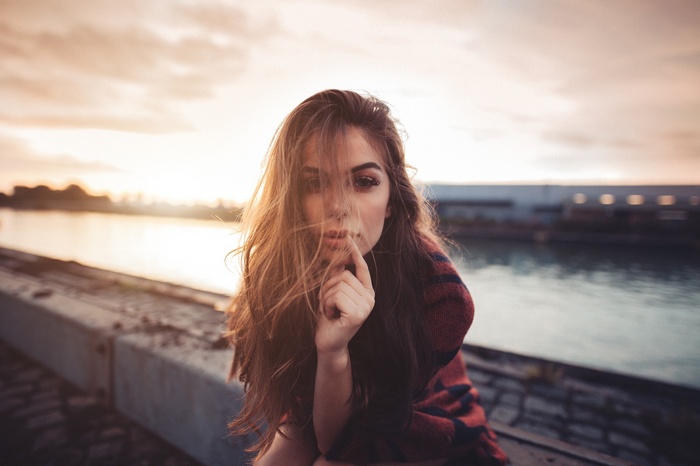 Woman with hair in face at sunset by river