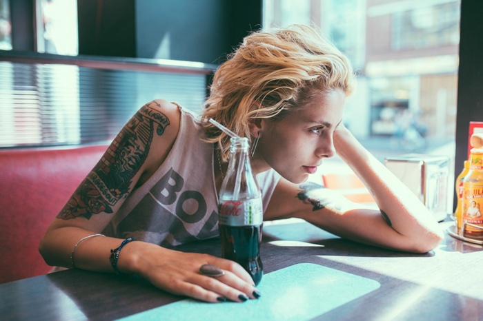 Woman with tattoos and Coca-Cola bottle in a diner