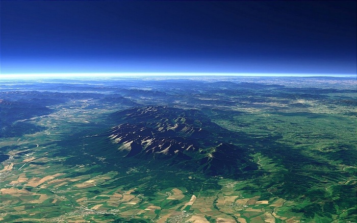 Aerial view of mountains and fields under a blue sky