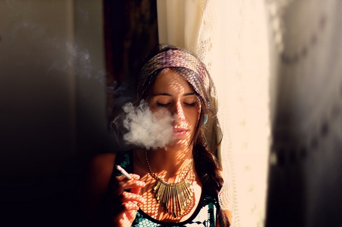 Woman smoking with eyes closed in sunlight