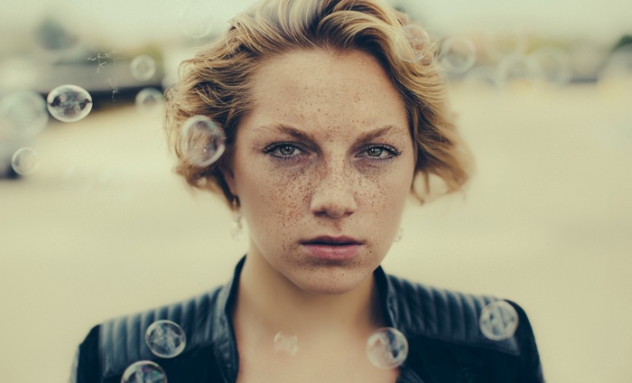 Woman with freckles and blonde wavy hair surrounded by bubbles