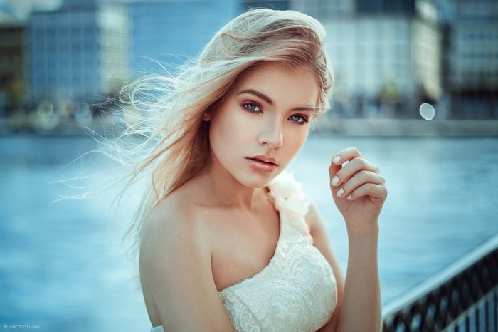 Portrait of a blonde woman with blue eyes in a white dress
