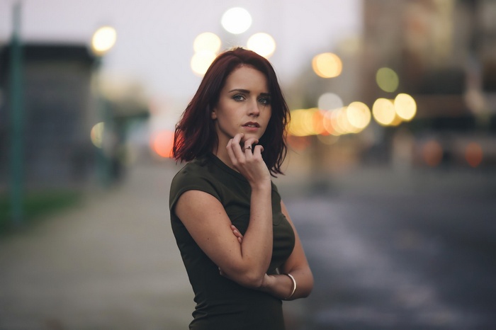 Woman with auburn hair standing outdoors at night