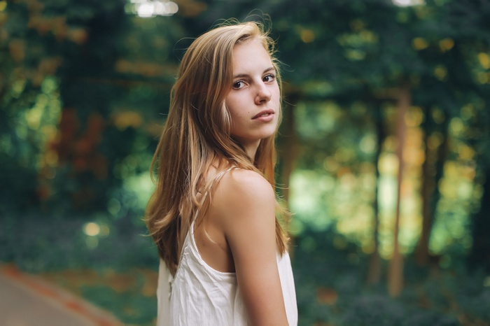 Woman with blonde hair looking over her shoulder outdoors