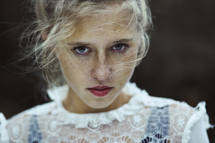 Woman with blonde hair and freckles looking at viewer