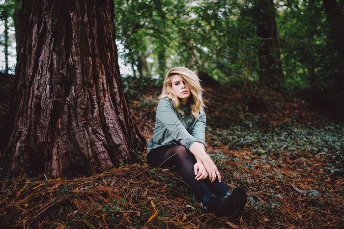 Hands on legs, looking away, women outdoors, forest, pantyhose, hair in face, sitting, women, blonde