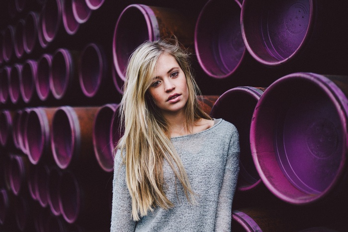 Woman leaning against purple pipes