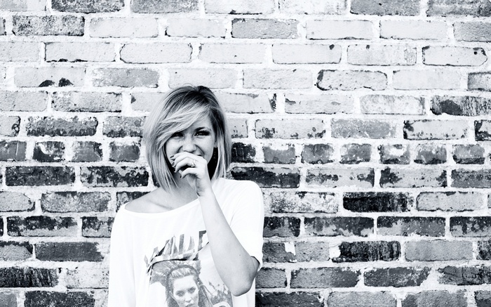 Woman smiling in front of a brick wall