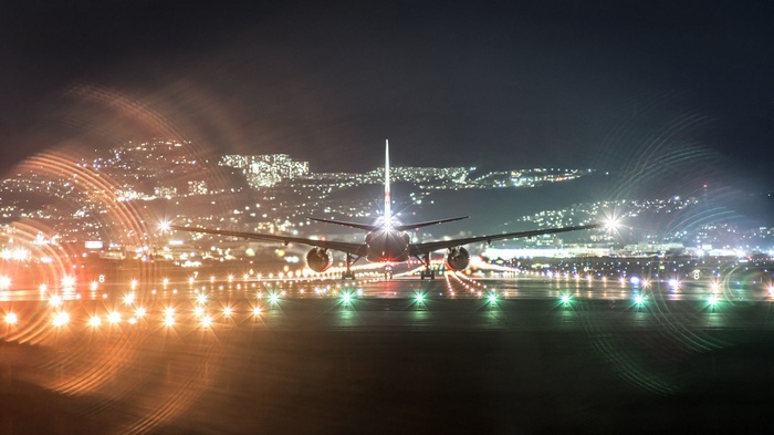 Airplane on runway at night with city lights