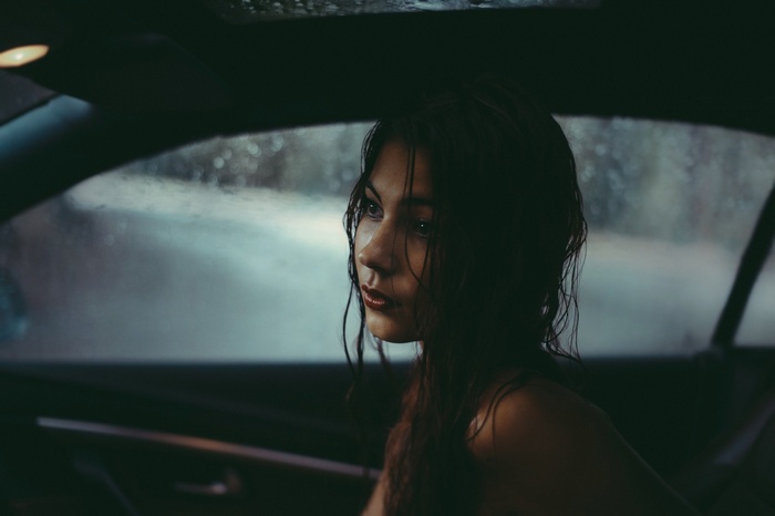 Woman with wet hair in a car during rain