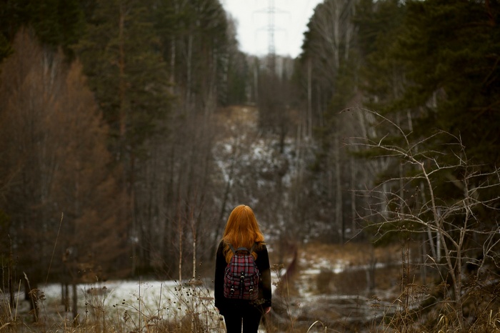 Woman with red hair and backpack in a forest