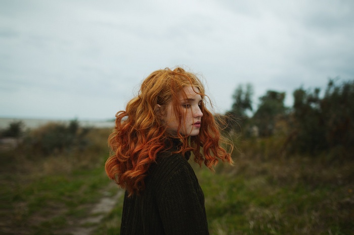 Redhead woman with freckles in a sweater outdoors