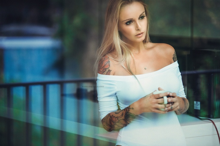 Woman with tattoos holding a cup