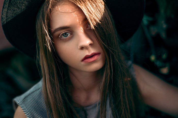 Portrait of a young woman with long blonde hair and a hat