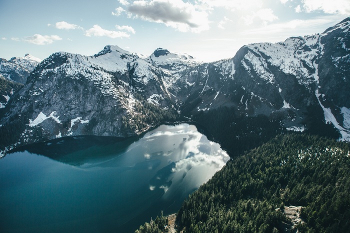 Snow-capped mountains surrounding a deep blue lake with evergreen forests