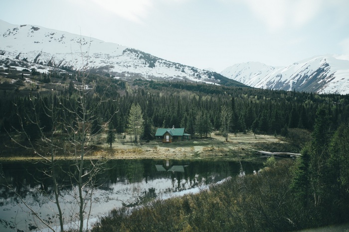 Cabin by a lake in a snowy mountain forest