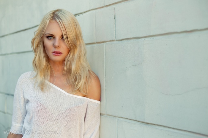 Woman with blonde hair leaning against a wall