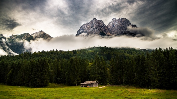Cabin in the mountains with forest and clouds