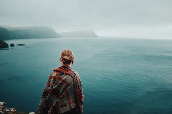 Woman in poncho looking at the ocean