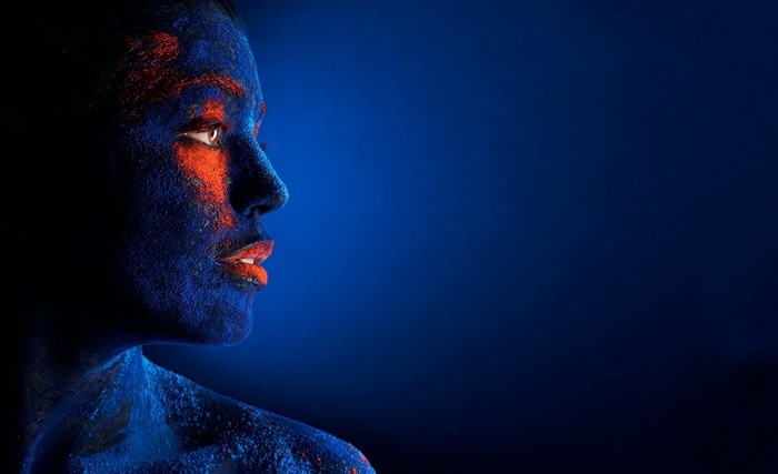 Woman with blue and orange face paint in profile