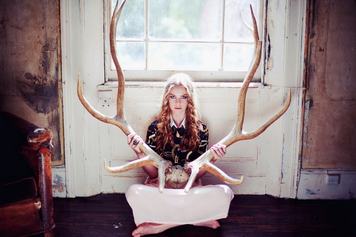 Woman holding large antlers in front of a window